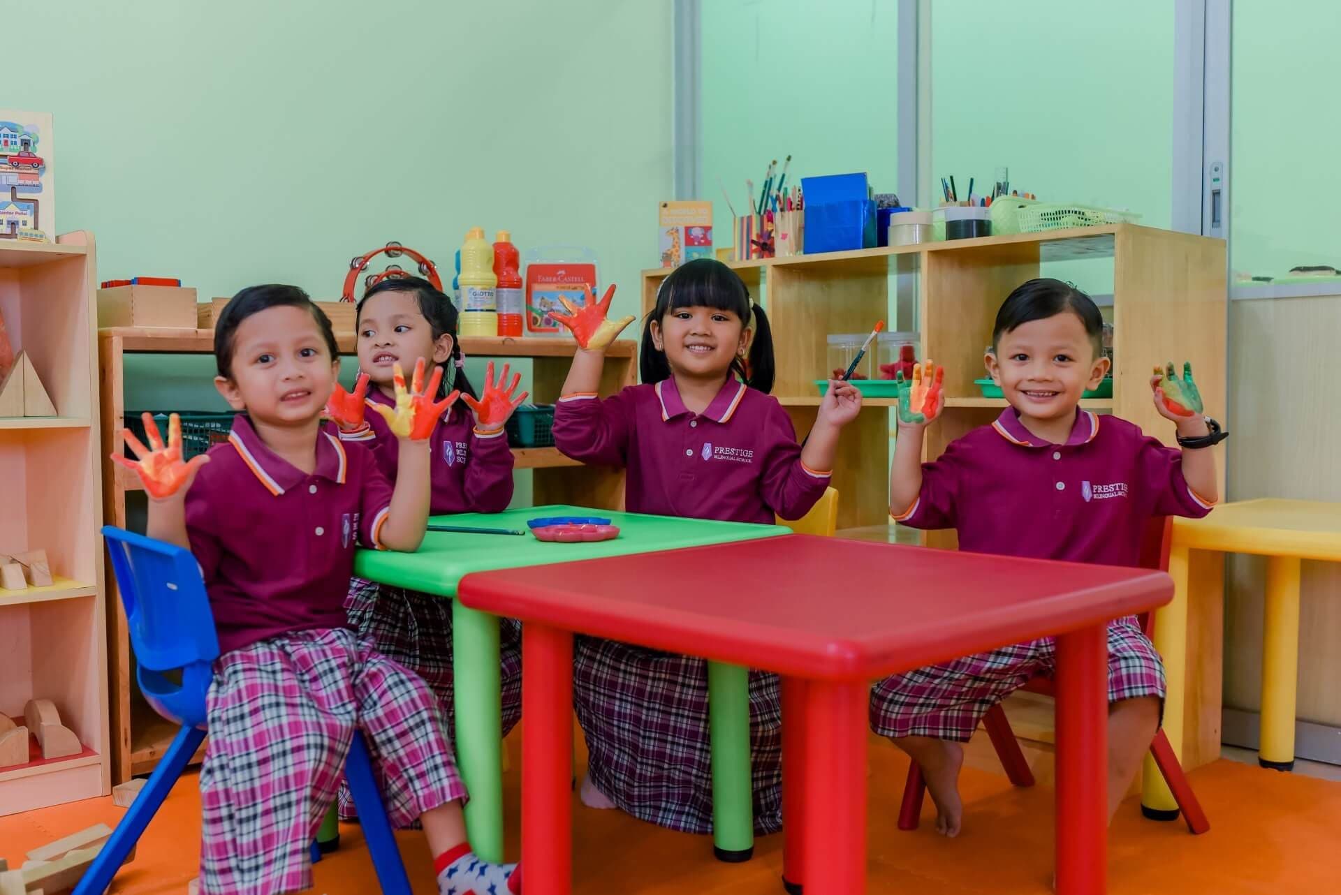 Empat siswa Taman Kanak-kanak menunjukkan tangan mereka yang penuh cat