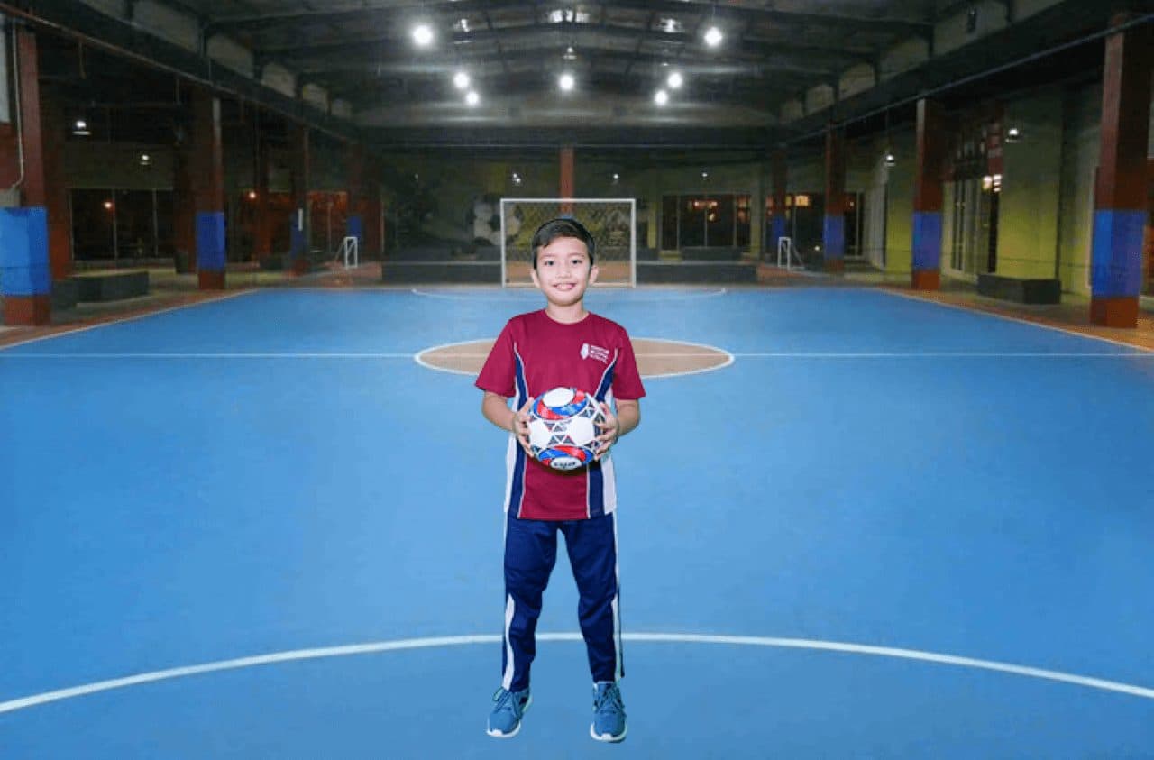 Seorang siswa membawa bola di lapangan futsal